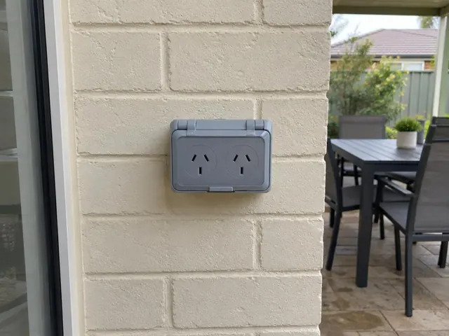 Outdoor double power point on a painted brick patio wall beside a glass door in Kotara